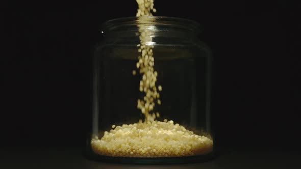 SLOW MOTION: Couscous Grains Pouring Into A Glass Jar