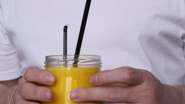A Man Holds a Glass of Mango Smoothie in a Cafe