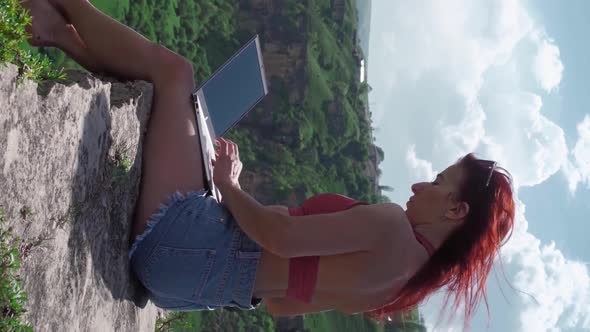 Girl Blogger Traveler is Typing Text on Laptop While Sitting on Top Mountain