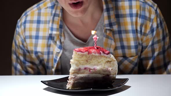 Guy in Checkered Shirt Blows Out Pink Burning Cake Candle