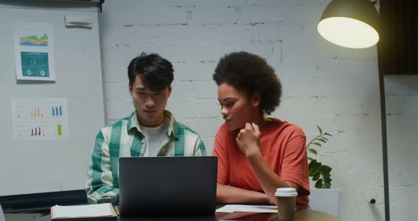 A Young Man and Woman Work in a Think Tank Discussing Documents