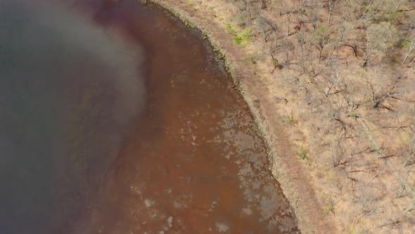 An aerial view of a reflective lake during the day. The drone, while tilted down, dolly in along the