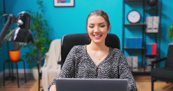 Portrait of Young Pretty Brunette Girl Video Chatting with Friends While Sitting at a Desk