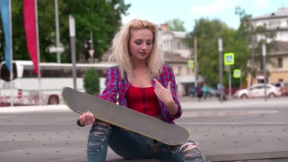 Teenage Girl Playing Air Guitar on Skate Outside on Open Space