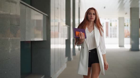 Beautiful business woman with red hair in fashion clothes walk work near office