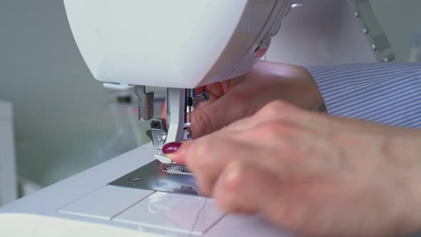 Hands of Young Woman Seamstress Threading Her Sewing Machine