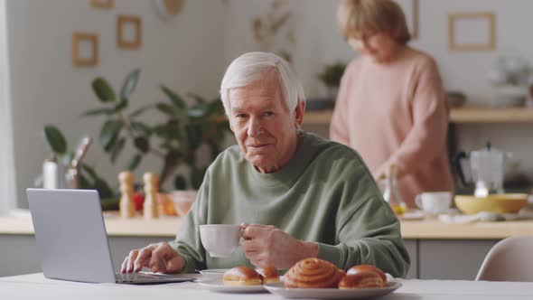 Portrait of Senior Man with Laptop and Tea Cup at Home