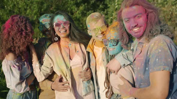 Portrait of Happy People Covered with Powder Paint Hugging and Smiling Standing Outdoors