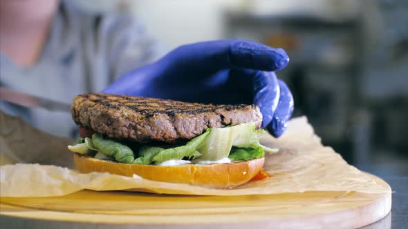 Closeup Shot of Chef's Hands Preparing a Delicious Burger with Cheese