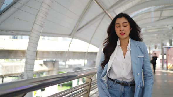 4K Asian business woman checking time on hand watch while walking in railway station in the morning.