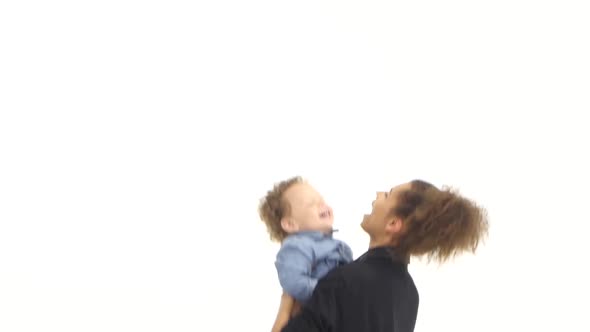 Mom of an African American Throws Her Baby Up, He Likes It Laughs. White Background