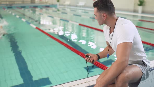 Young Professional Female Swimmer Swims in the Pool Coach Keeps Track of Time of the Standard for