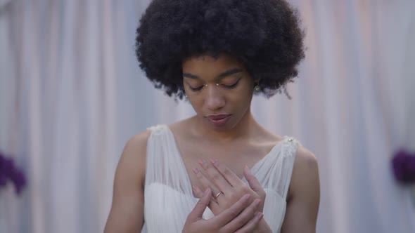 Elegant Confident African American Bride in White Dress Looking at Wedding Ring on Finger Caressing