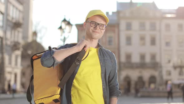 Portrait of a Happy Young Delivery Man Who is Standing and He Throws His Backpack Over His Shoulder