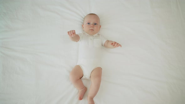 Top View of the Newborn Baby is Lying on a White Bed and Blanket Comfortable and Safety