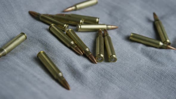 Cinematic rotating shot of bullets on a fabric surface - BULLETS 100