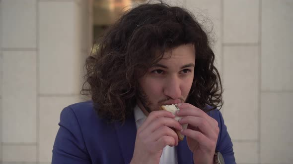 Young Businessman Eats Fast Food Outdoors