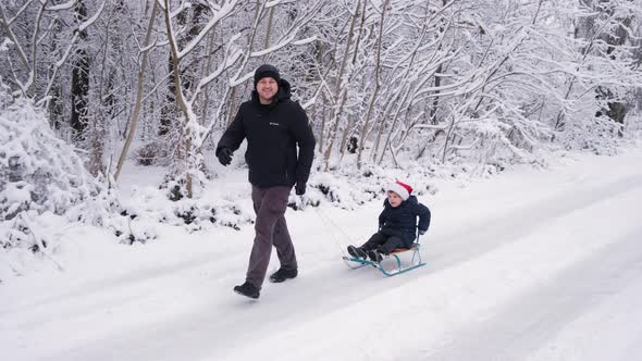 Dad Sledding His Son at a Ski Resort in a Snowcovered Winter Forest