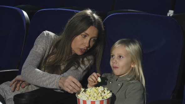 Beautiful Woman and Her Little Daughter Eating Popcorn Watching Movie at the Cinema