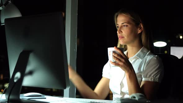 Businesswoman having coffee while working over computer