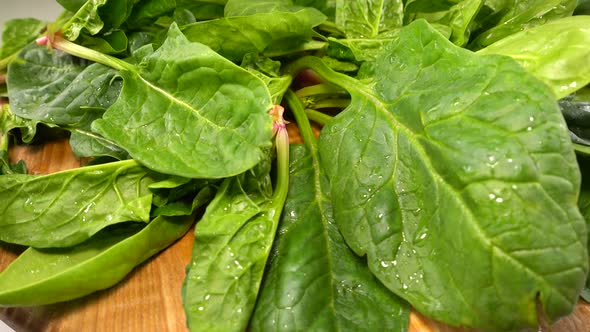 Spinach leaves on a wooden cutting board.