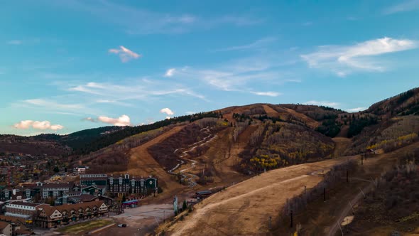 Aerial hyperlapse and cloudscape over a ski resort and mountain community in autumn