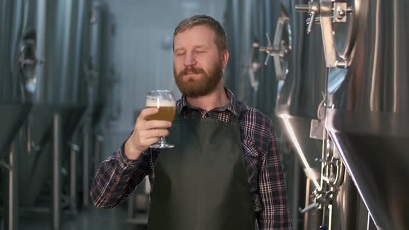 Portrait of a Successful Businessman Brewer with a Beard Demonstrates the Quality of Freshly Brewed