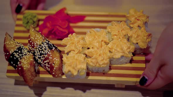 Waiter Serves the Table with a Dish of Japanese Cuisine