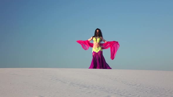 Brunette with a Veil in Her Hands Dances a Belly Dance in the Desert. Slow Motion