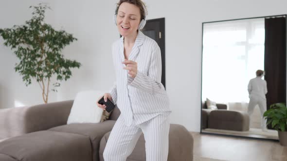 Happy Young Woman In Earphones Listening To Music With Smart Phone, Dancing And Smiling