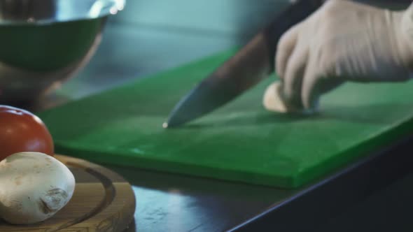 Cropped Shot of a Chef Slicing Muschrooms on Cutting Board