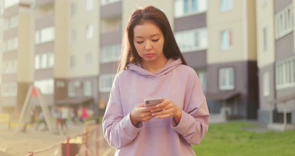 Asian Woman Using Smartphone Outdoors