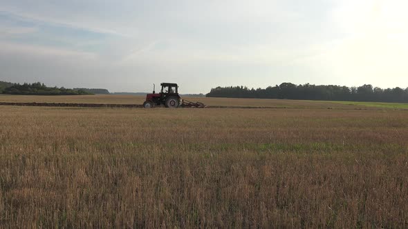 Tractor Vehicle Turn Up Fertile Soil with Plough in Autumn Field. 