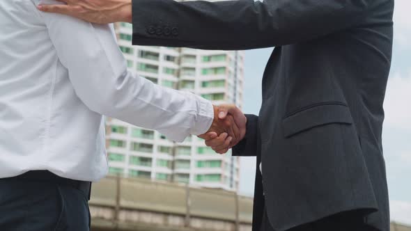 Close up shot of Asian businessmen partnership making handshake in the city building in background.