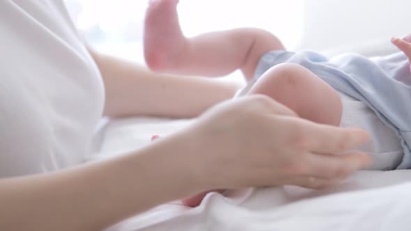 Mother Changes Diapers to Her Newborn Baby Little Boy on Changing Table in Clean Dry Nappy Mom