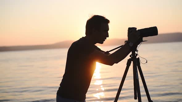 A Young Man With Camera Enjoy Taking Video On The Sunset In Lake Bracciano, Italy - Wide Shot