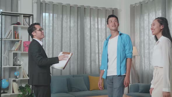 Asian Real Estate Agent Welcoming A Couple Who Walks Inside Before Talking About The House For Sale