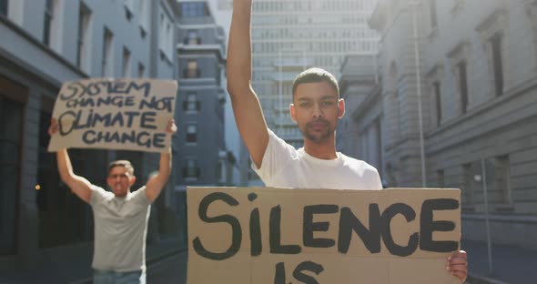 Two mixed race men on a protest march holding placards raising hands and shouting