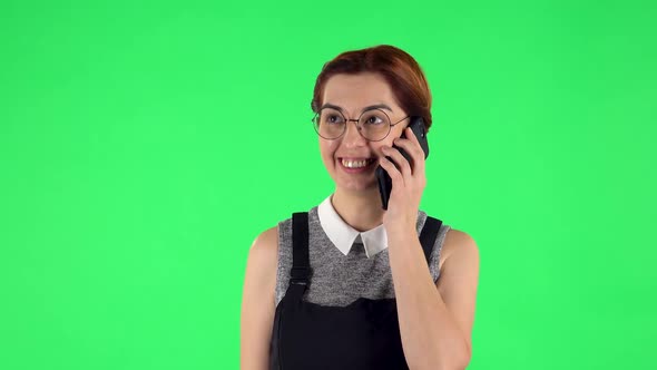 Portrait of Funny Girl in Round Glasses Is Talking for Mobile Phone. Green Screen