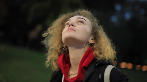 Curly Woman Looks Around in Evening Park