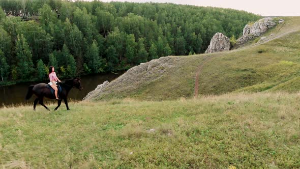 Drone Video of a Girl Riding Horse on a Mountain in the Summer at Sunset. Horseback Riding