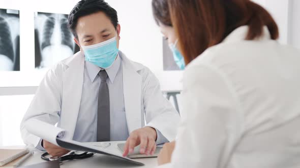 Asia male doctor wear protective mask using tablet is delivering symptoms with female patient