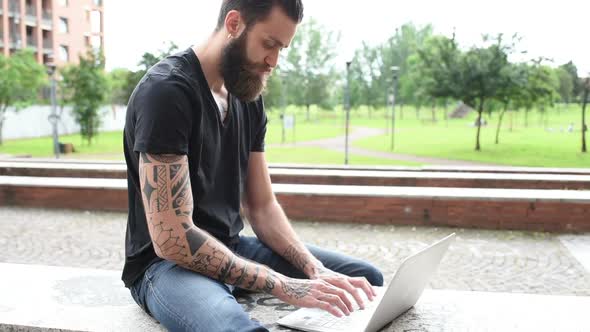 young beautiful smart creative business man sitting outdoor using personal computer