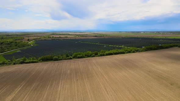 Aerial view of big sustainable electric power plant with many rows of solar photovoltaic panels alt