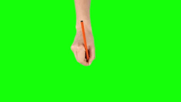 Female Hand with Orange Pencil Is Writing on Green Screen Background. Close Up