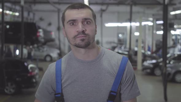 Close-up Portrait of Young Caucasian Repairman with Brown Eyes Looking at Camera. Confident Auto