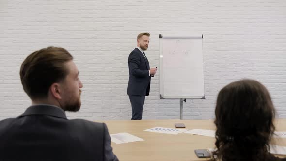 Young Businessman Standing Near a Flip Chart and Explaining the Business Plan