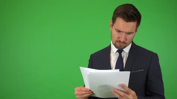 A Young Businessman Goes Through a Bunch of Papers, Then Frowns at the Camera - Green Screen Studio