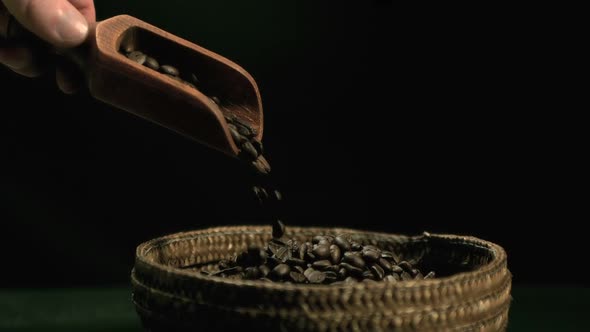 Hand pouring coffee beans from wooden spoon to basket