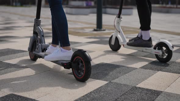 A Man and a Woman Ride Electric Scooters